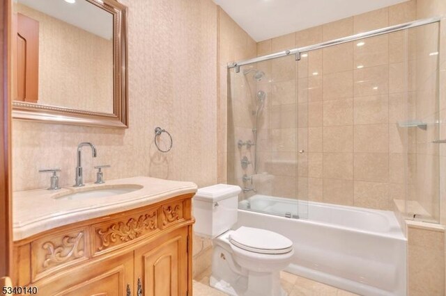 full bath with toilet, bath / shower combo with glass door, and vanity