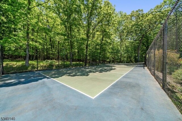 view of basketball court with a tennis court and fence