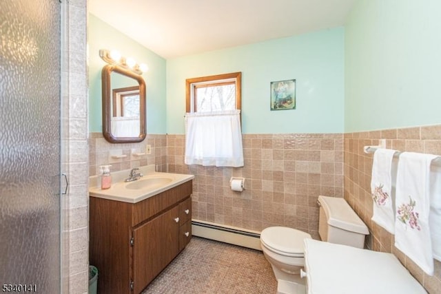 full bath with vanity, a shower stall, a baseboard heating unit, tile walls, and toilet