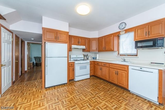 kitchen featuring white appliances, light countertops, under cabinet range hood, and a sink