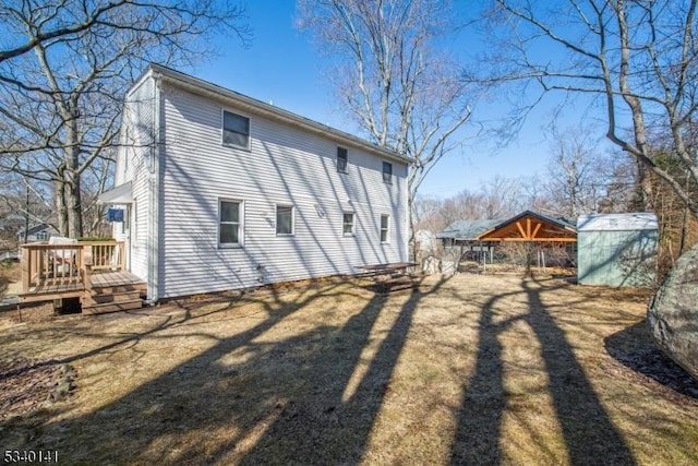 back of house featuring a deck and an outdoor structure