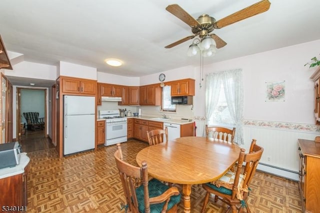 dining room featuring a ceiling fan, baseboard heating, and wainscoting