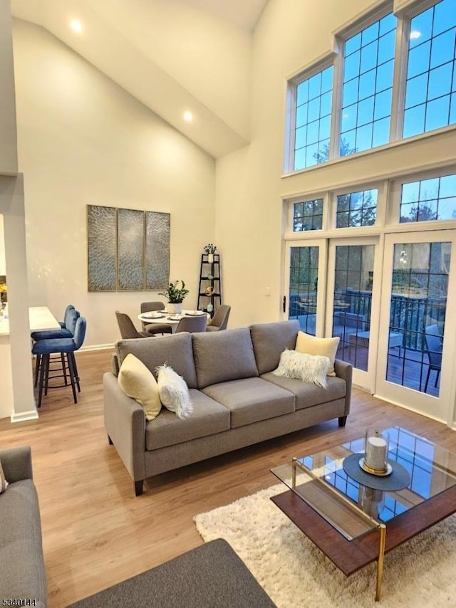 living room featuring light wood finished floors, baseboards, high vaulted ceiling, and recessed lighting