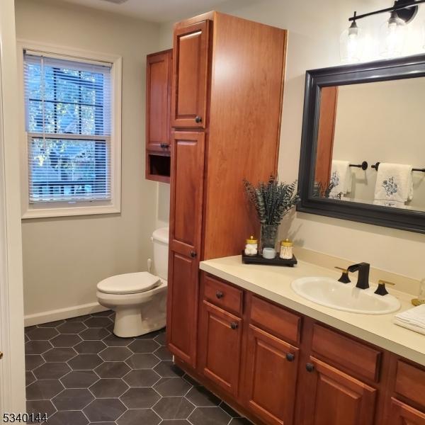 bathroom with toilet, tile patterned flooring, baseboards, and vanity