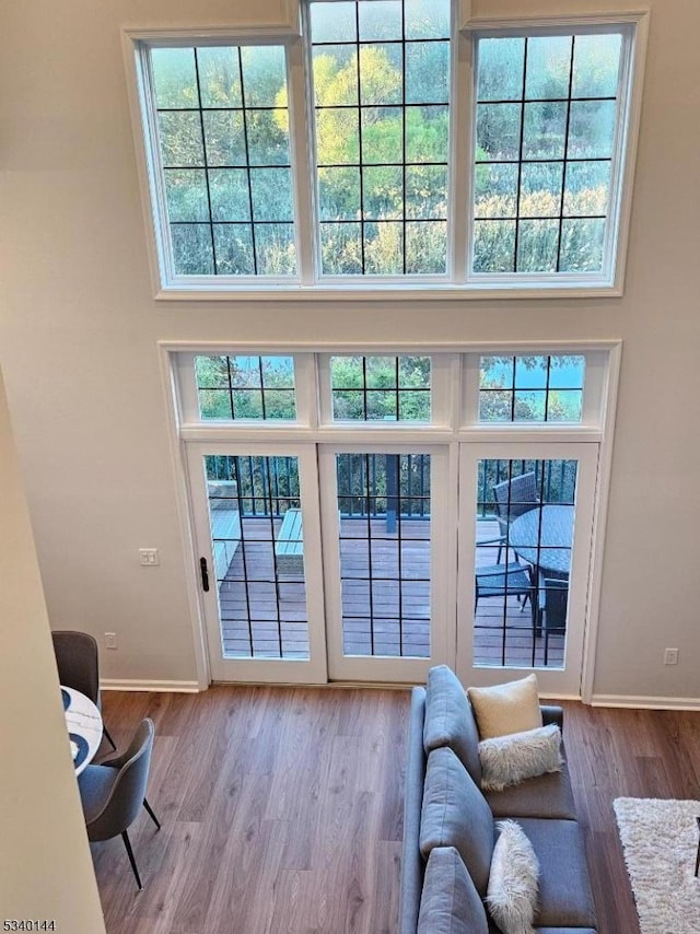 entryway featuring light wood-type flooring, a towering ceiling, and baseboards