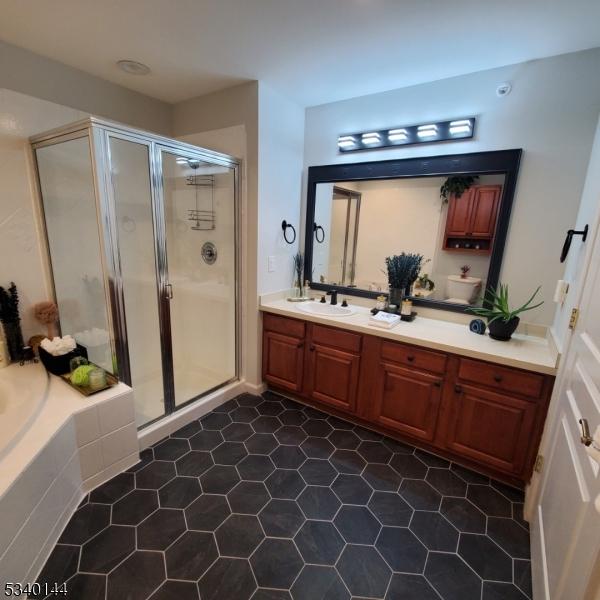 bathroom featuring double vanity, a stall shower, a sink, and a bath