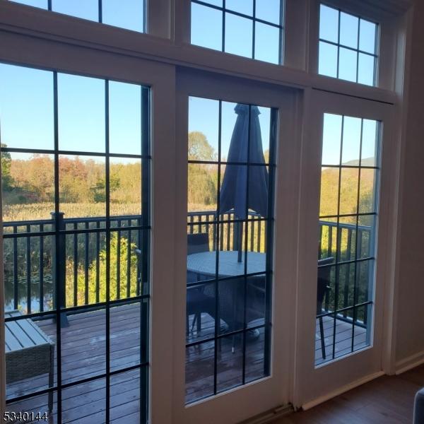 doorway to outside featuring a towering ceiling, a water view, and wood finished floors