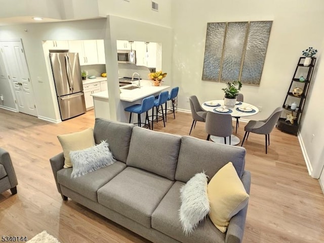 living room featuring light wood-style flooring, visible vents, and baseboards