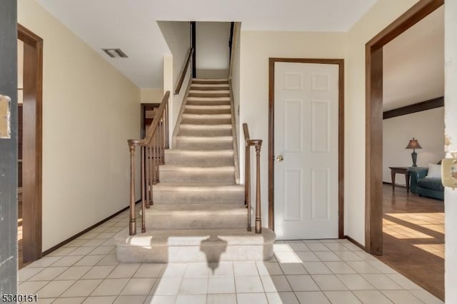 stairs featuring tile patterned flooring, visible vents, and baseboards