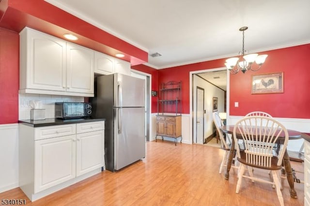 kitchen with white cabinets, dark countertops, freestanding refrigerator, light wood-type flooring, and black microwave