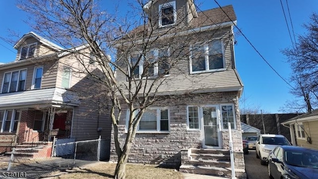 view of front of house with stone siding and fence