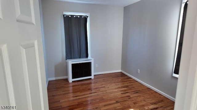 unfurnished room featuring radiator, baseboards, and wood finished floors