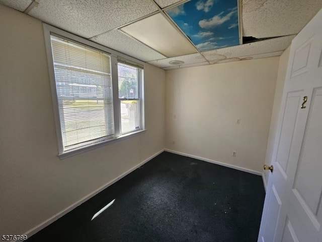 empty room featuring a drop ceiling and baseboards