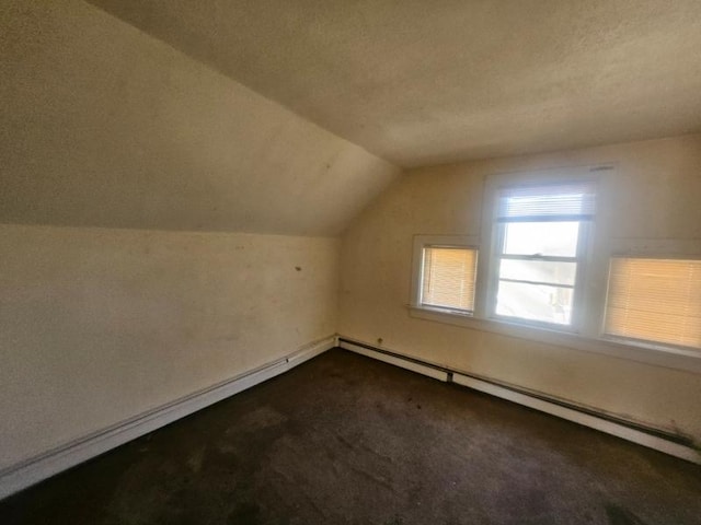 bonus room with lofted ceiling, a baseboard heating unit, dark carpet, and baseboards