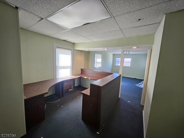 office featuring a paneled ceiling, dark carpet, and built in desk