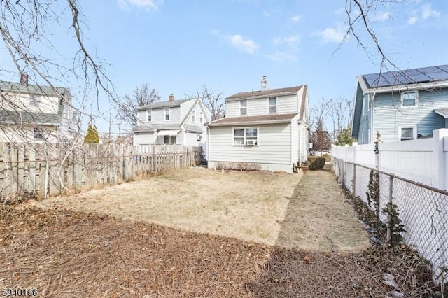 rear view of house with a fenced backyard