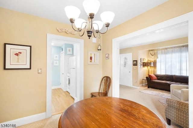 dining room with light carpet, baseboards, and an inviting chandelier