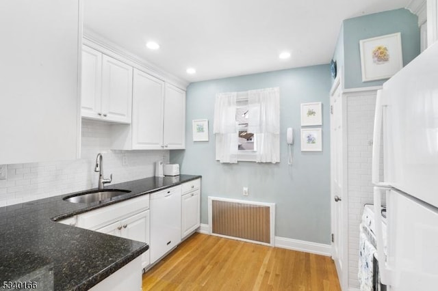 kitchen featuring visible vents, dark stone counters, light wood-type flooring, white cabinetry, and a sink