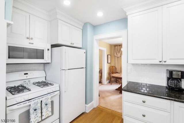 kitchen with white appliances, dark stone counters, light wood-style floors, white cabinetry, and backsplash