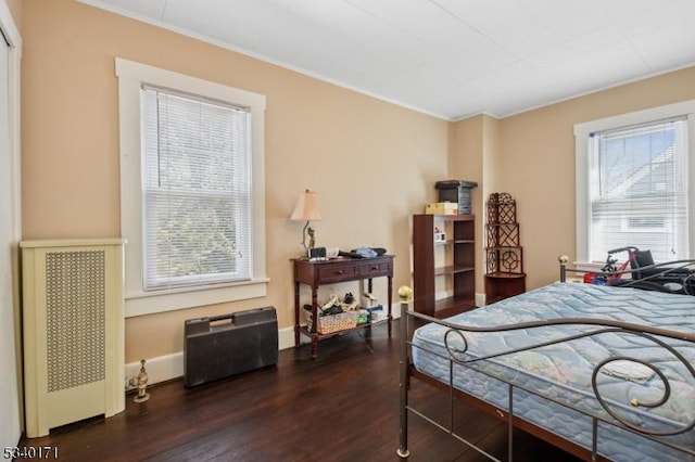 bedroom featuring dark wood-type flooring, ornamental molding, and baseboards