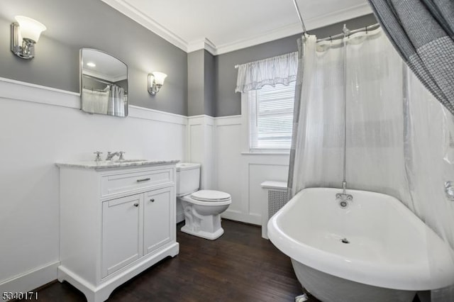 bathroom with a wainscoted wall, radiator heating unit, ornamental molding, wood finished floors, and a freestanding bath