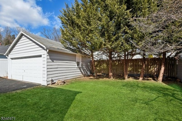 view of yard featuring a garage, fence, and an outbuilding