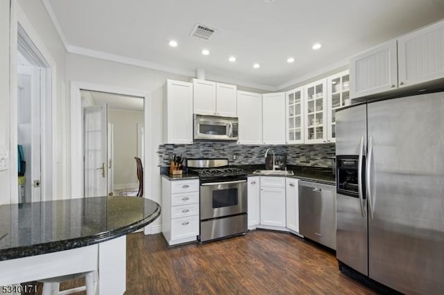 kitchen featuring dark wood-style floors, stainless steel appliances, visible vents, glass insert cabinets, and a sink