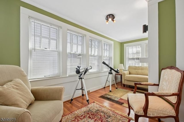 living area with baseboards, light wood-style flooring, and crown molding