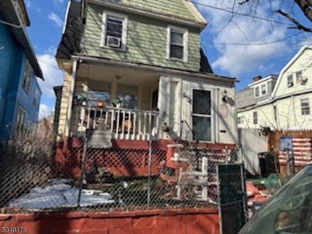 back of property featuring a porch and a fenced front yard