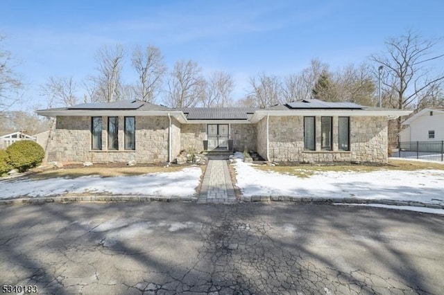 mid-century home featuring stone siding and roof mounted solar panels