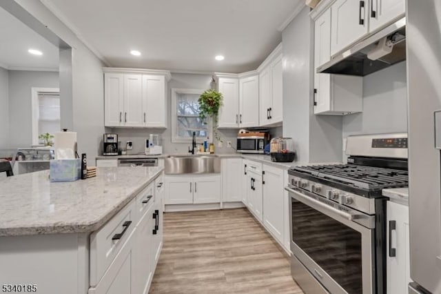 kitchen featuring appliances with stainless steel finishes, ornamental molding, under cabinet range hood, white cabinetry, and a sink