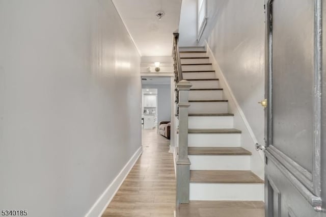 staircase featuring baseboards and wood finished floors