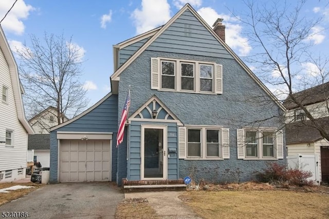 view of front of property featuring driveway, an attached garage, and a chimney