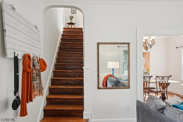 staircase with arched walkways and an inviting chandelier