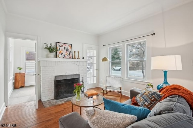 living area with a brick fireplace, baseboards, and wood finished floors