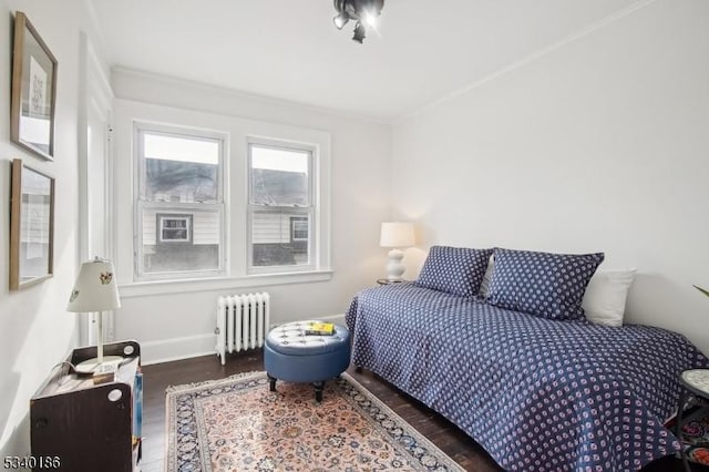 bedroom with radiator, baseboards, dark wood finished floors, and crown molding