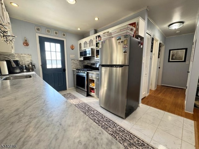 kitchen featuring crown molding, light countertops, decorative backsplash, appliances with stainless steel finishes, and white cabinetry