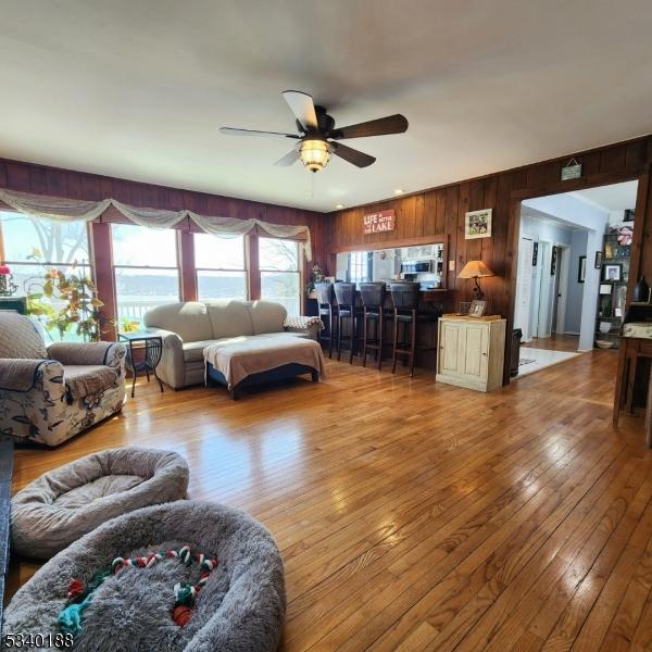 living area with wood walls, ceiling fan, and hardwood / wood-style floors