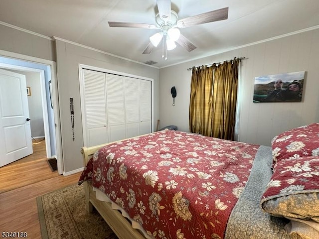 bedroom with ceiling fan, a closet, wood finished floors, and crown molding