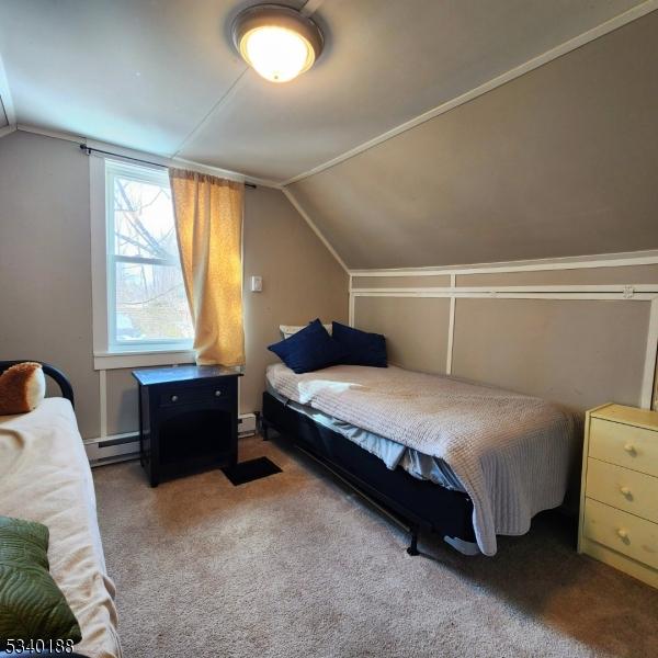 carpeted bedroom with lofted ceiling, a baseboard heating unit, and baseboard heating