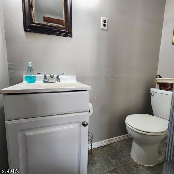 half bathroom featuring toilet, vanity, and baseboards