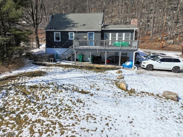 snow covered back of property featuring a deck and stairway