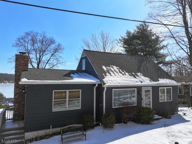 view of front of house with a shingled roof and a chimney