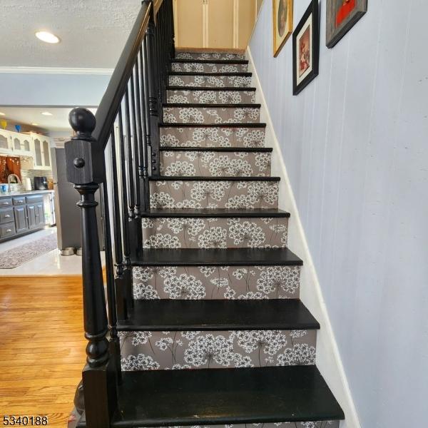 stairs featuring a textured ceiling and wood finished floors