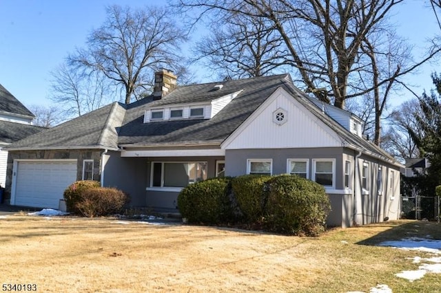 view of front facade with driveway, a chimney, an attached garage, and roof with shingles