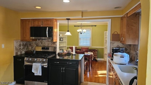 kitchen with an inviting chandelier, light wood-style floors, tasteful backsplash, and stainless steel appliances