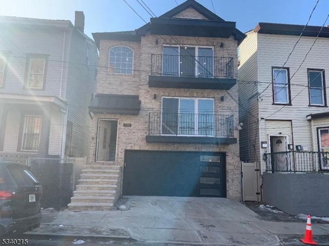 view of property with a balcony, an attached garage, concrete driveway, and brick siding