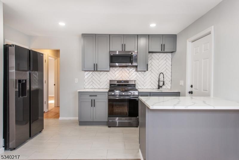 641-643 E 6th St, Plainfield City, NJ 07060 - kitchen featuring appliances with stainless steel finishes, tasteful backsplash, gray cabinetry, and light stone countertops