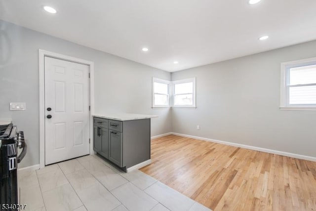 kitchen featuring recessed lighting, gray cabinets, light countertops, and gas range