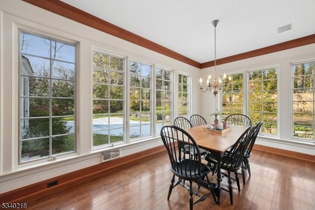 dining space with a healthy amount of sunlight, an inviting chandelier, dark wood-type flooring, and crown molding